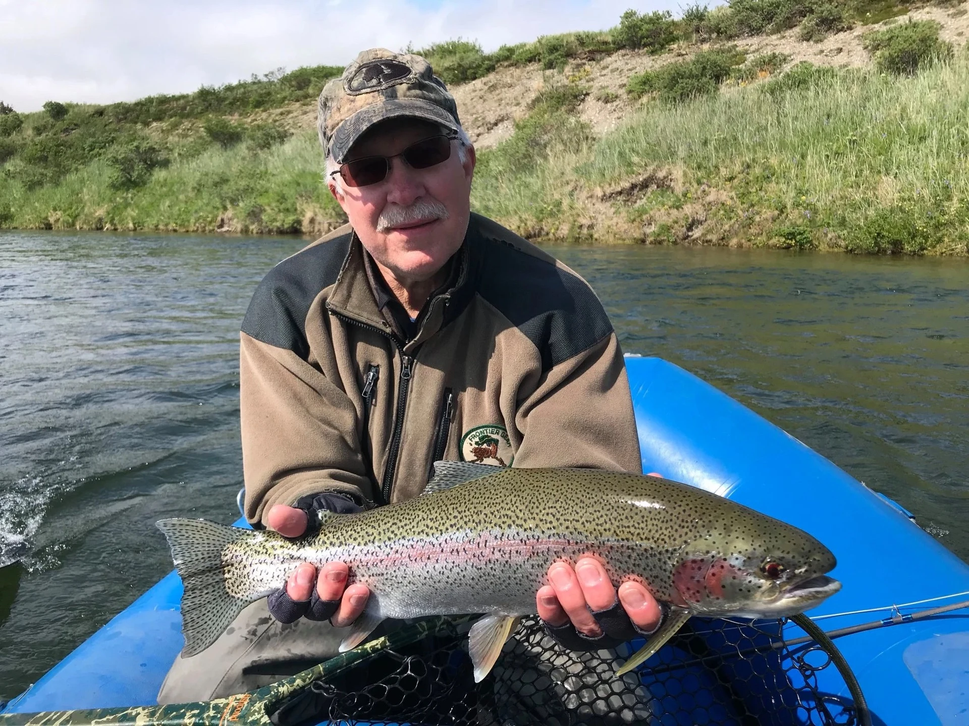 Guest holding trophy rainbow trout from blue raft on Alaska river — 2019 season