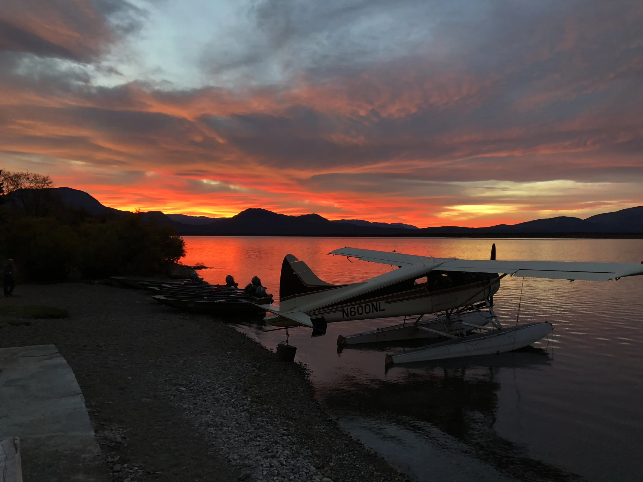 Newhalen Lodge floatplanes docked at a dramatic red and orange Alaskan sunset