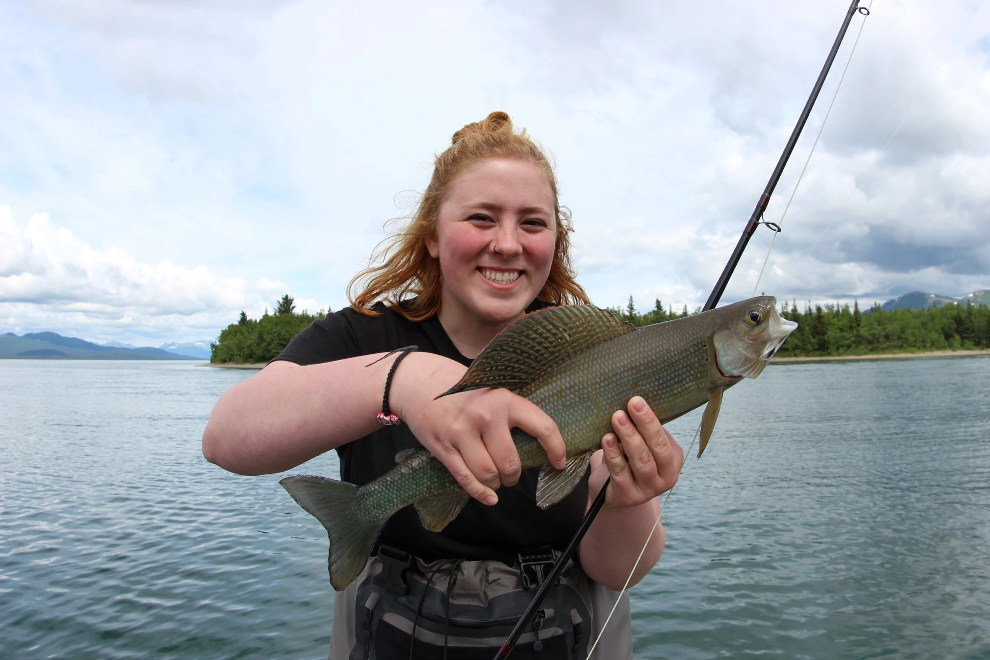 Young female guest proudly holding a beautiful Arctic Grayling with a large sail-like dorsal fin
